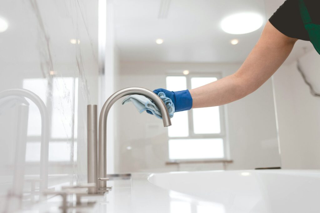 Girl in gloves cleans the faucet. Bathroom cleaning